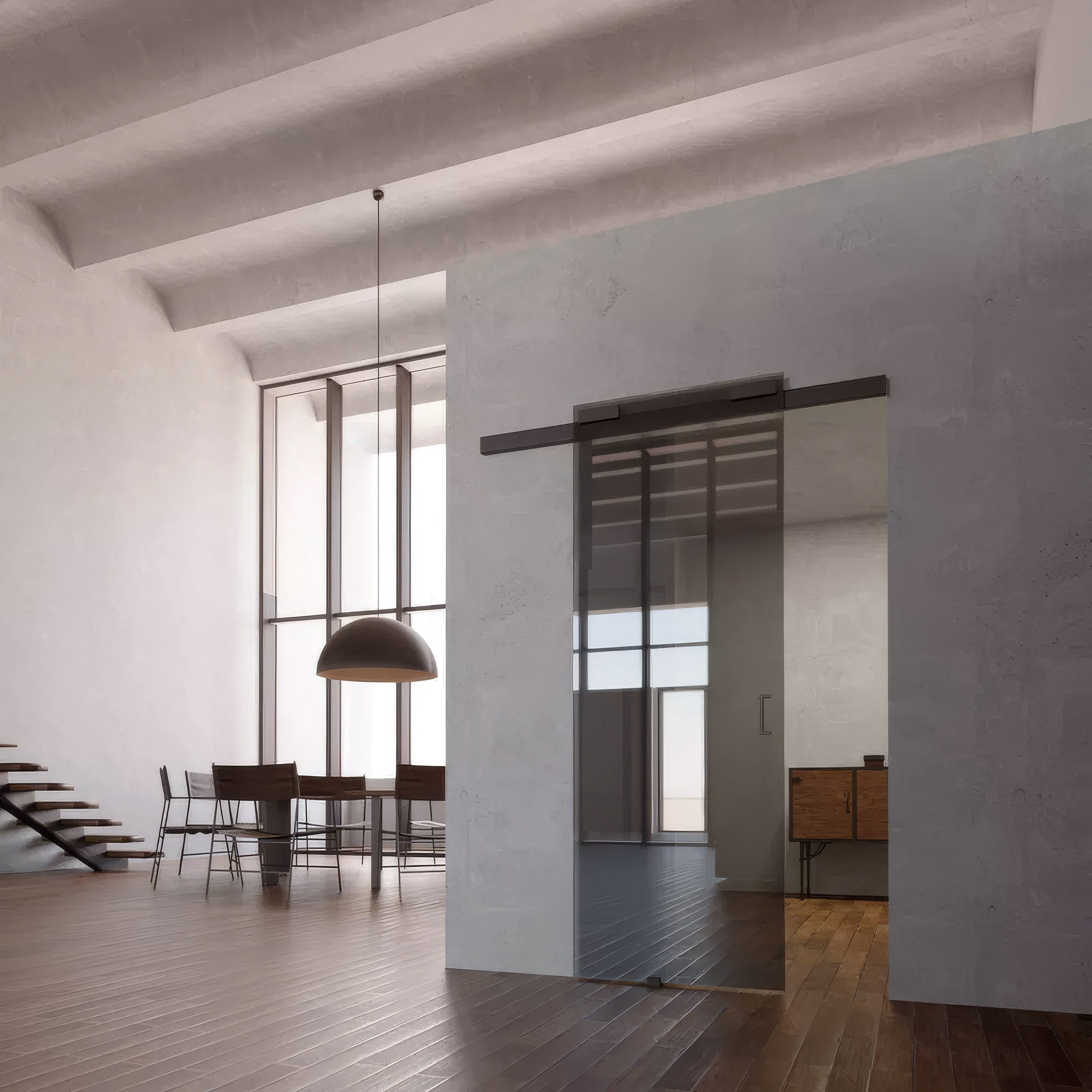 Modern interior with glass partition, dining table, and staircase.
