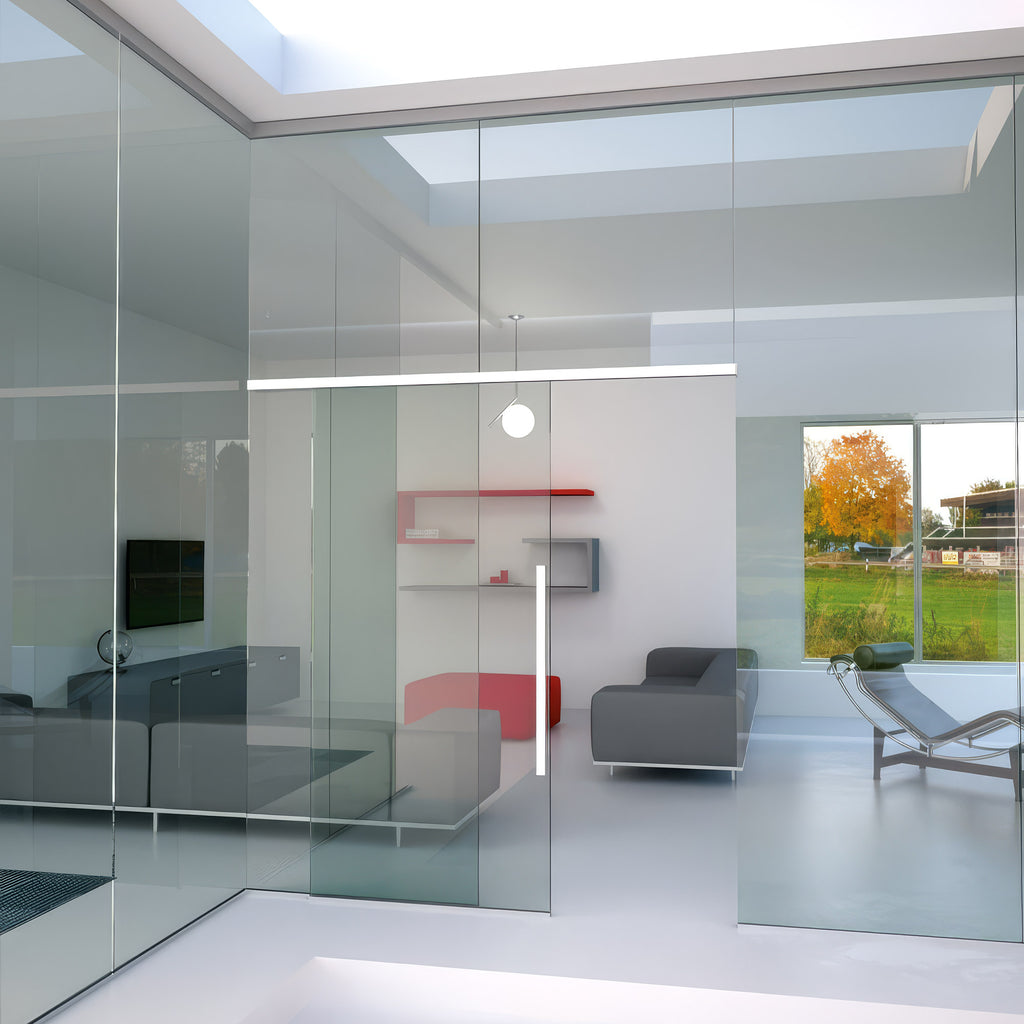 Modern interior design with glass walls, gray furniture, and a view of trees outside.