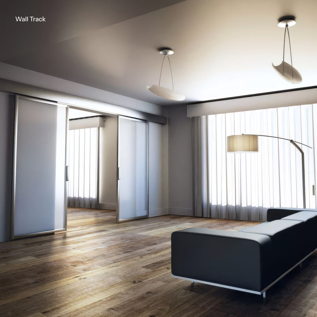 Modern living room with a black sofa, wooden floor, and large windows.