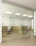 Modern office interior with glass walls and wooden desks.